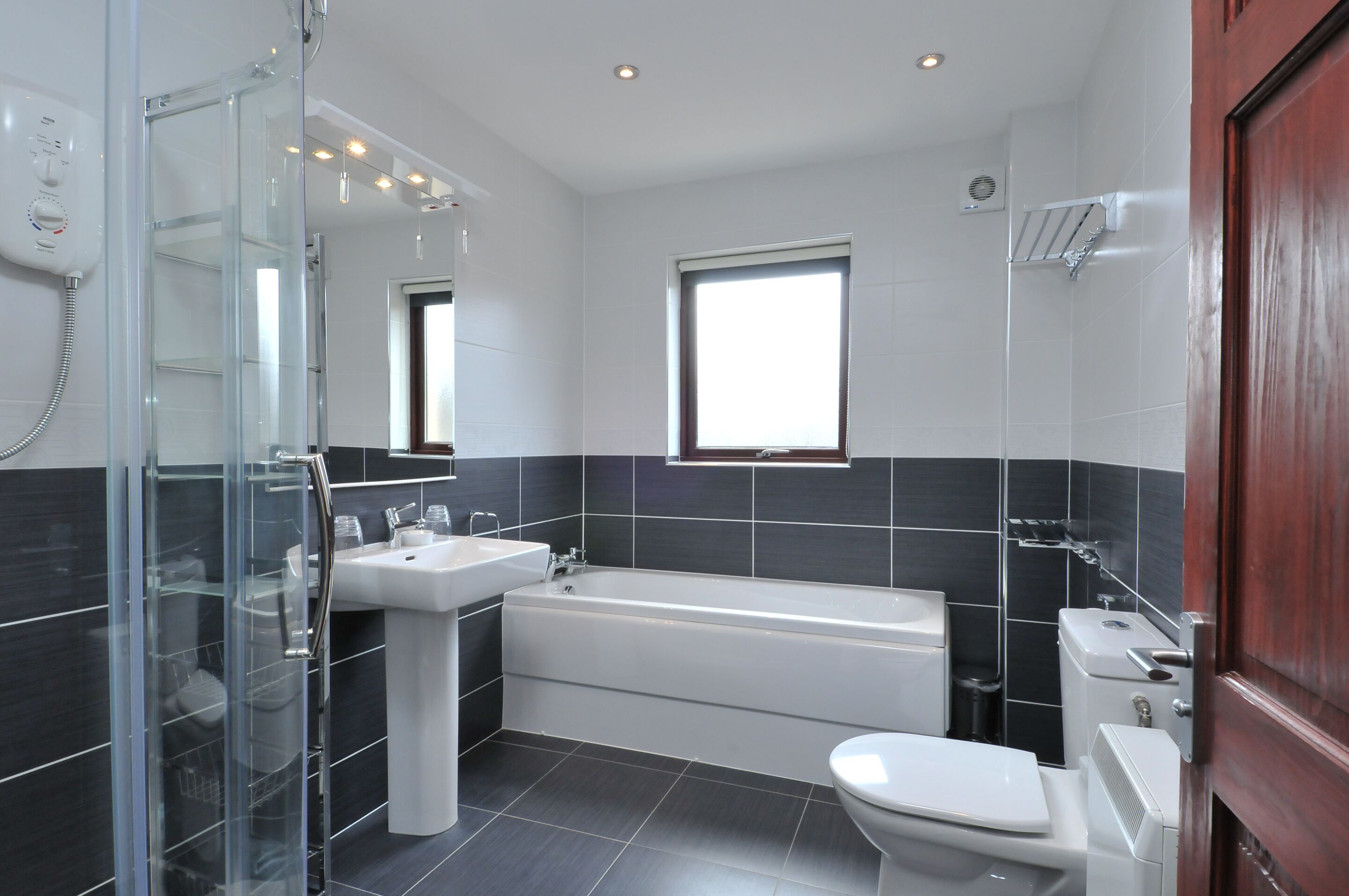 A modern bathroom with a glass shower enclosure, a bathtub, a toilet, and a sink.