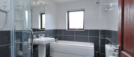 A modern bathroom with a glass shower enclosure, a bathtub, a toilet, and a sink.