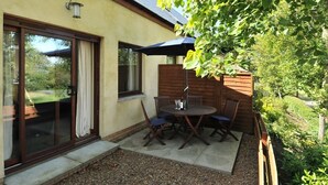 A patio with a table and chairs, a wooden fence, and a large umbrella.