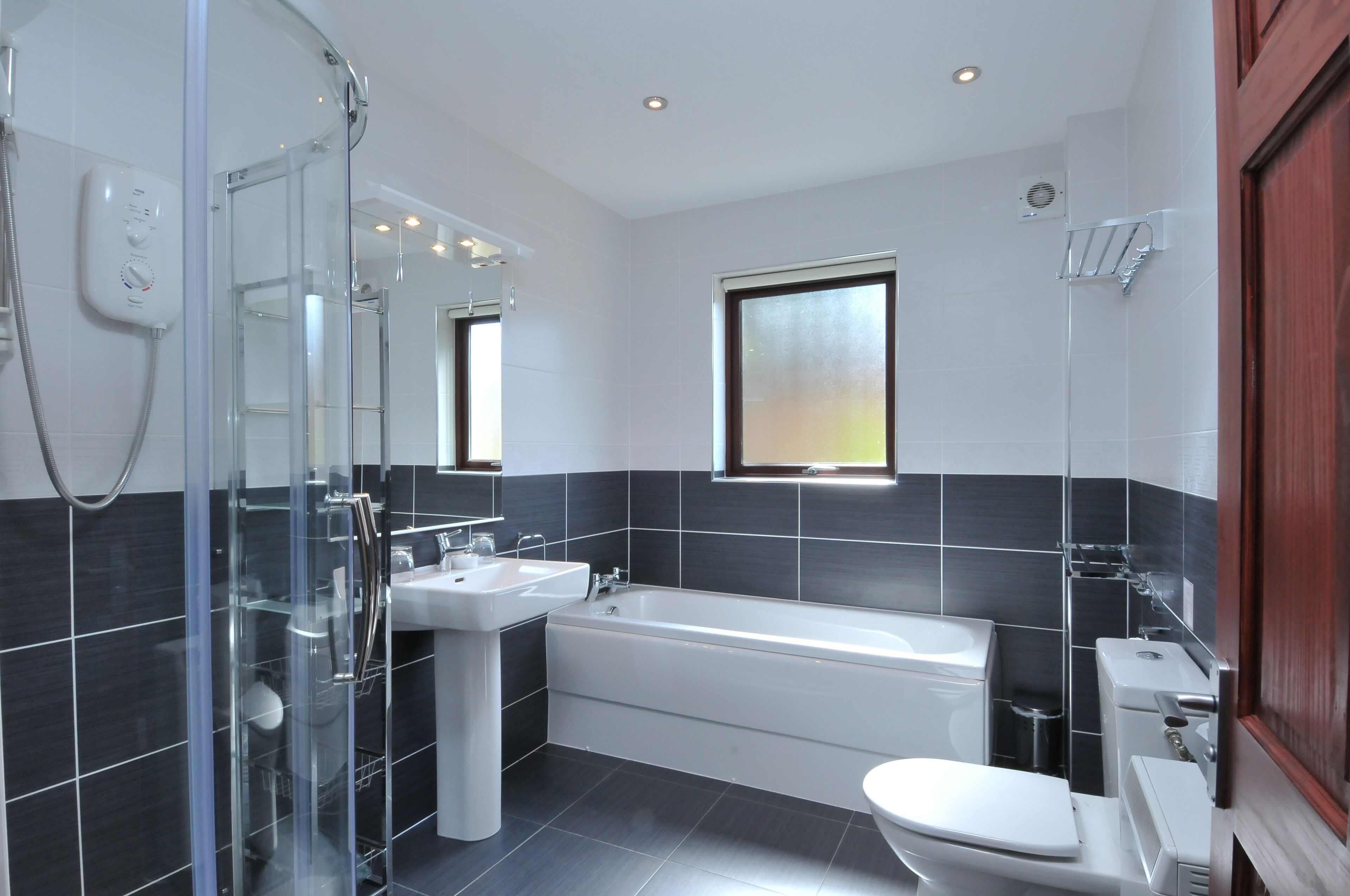 Ein modernes Badezimmer mit einer Glasdusche, einem freistehenden Waschbecken, einer Badewanne und einem WC.