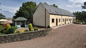 A building with a sloped roof, multiple windows, and a gravel driveway.