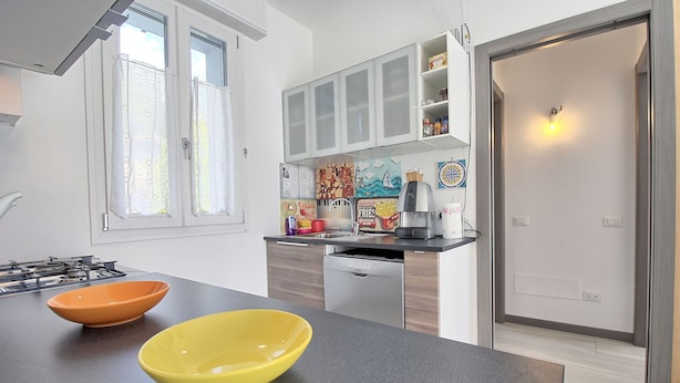 A modern kitchen with a black countertop, two bowls, a stove, and a dishwasher. - Logicasa Zazzi House (Como)