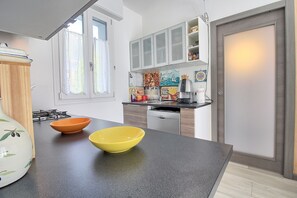 A modern kitchen with a black countertop, two bowls, a gas stove, and a dishwasher. - Logicasa Zazzi House (Como)