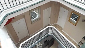 Een meerlaags interieur met een centrale trap, deuren met de nummers 103 en 101, en een klein raam op de bovenverdieping.