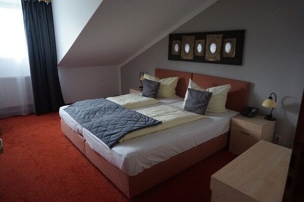 Une chambre à coucher avec un lit, des tables de chevet, une commode et une fenêtre avec des rideaux.