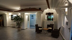 A spacious living area with a fireplace, comfortable seating, and a large potted plant. - Hotel Molitor (Bad Homburg v.d. Hoehe)