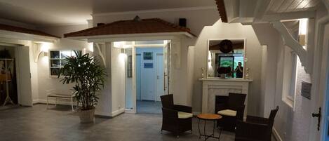 A spacious living area with a fireplace, comfortable seating, and a large potted plant.