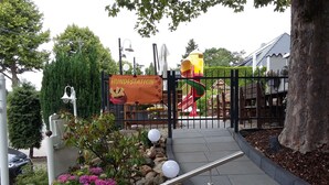 A gated entrance to a park with a playground, including a slide and a swing set. - Hotel Molitor (Bad Homburg v.d. Hoehe)