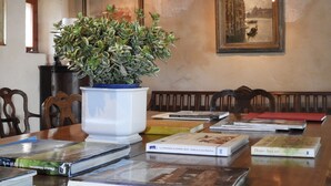 Een eetgedeelte met een houten tafel, boeken, een potplant en twee ingelijste foto's aan de muur.
