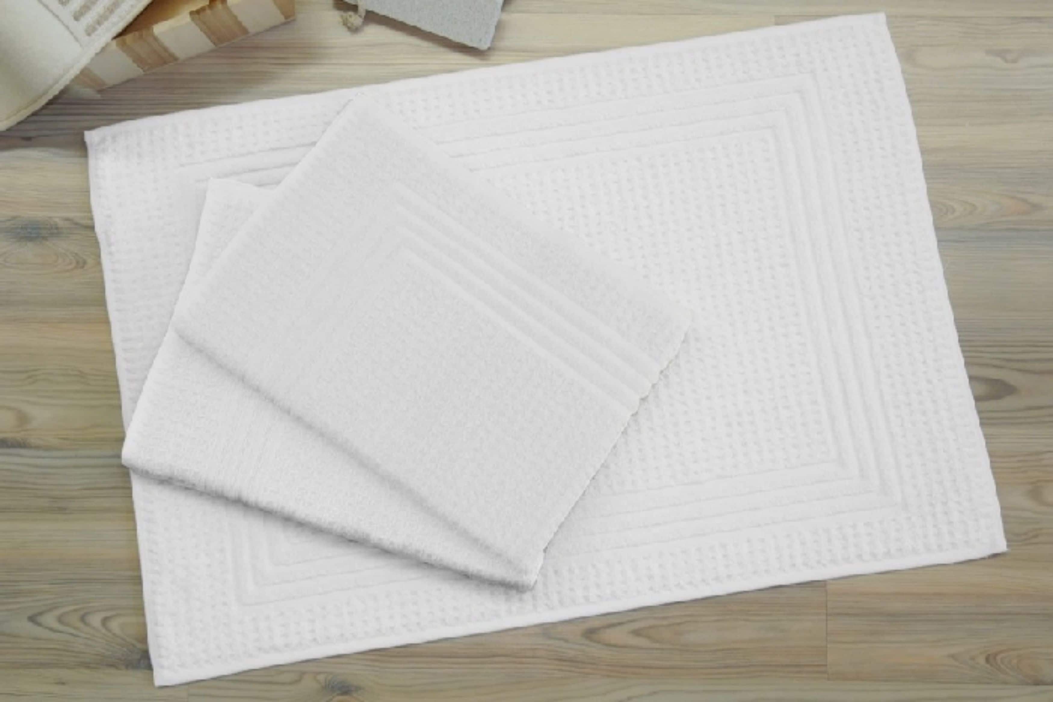 A stack of white textured mats on a wooden floor.