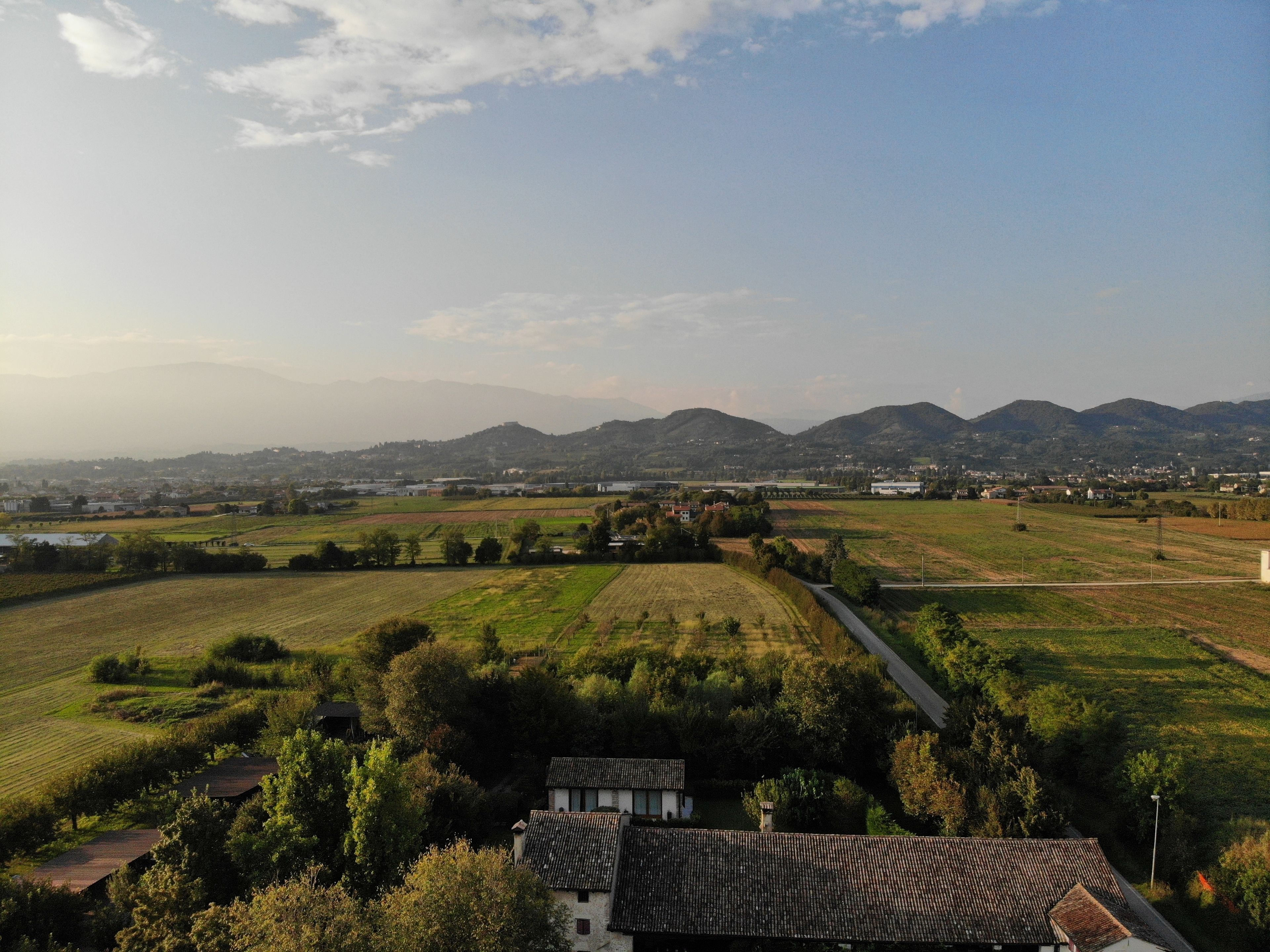 A rural landscape with fields, a road, and distant mountains.
