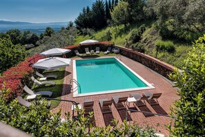 Una piscina al aire libre, sillones reclinables de piscina