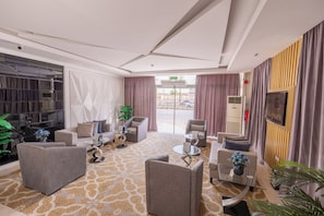 Un vestíbul d'hotel modern amb zona de seients, una taquilla d'informació i un gran finestral amb vista al carrer.