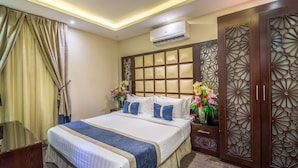 Habitación de hotel con una cama grande, una mesita de noche con un jarrón de flores y un panel decorativo de madera.