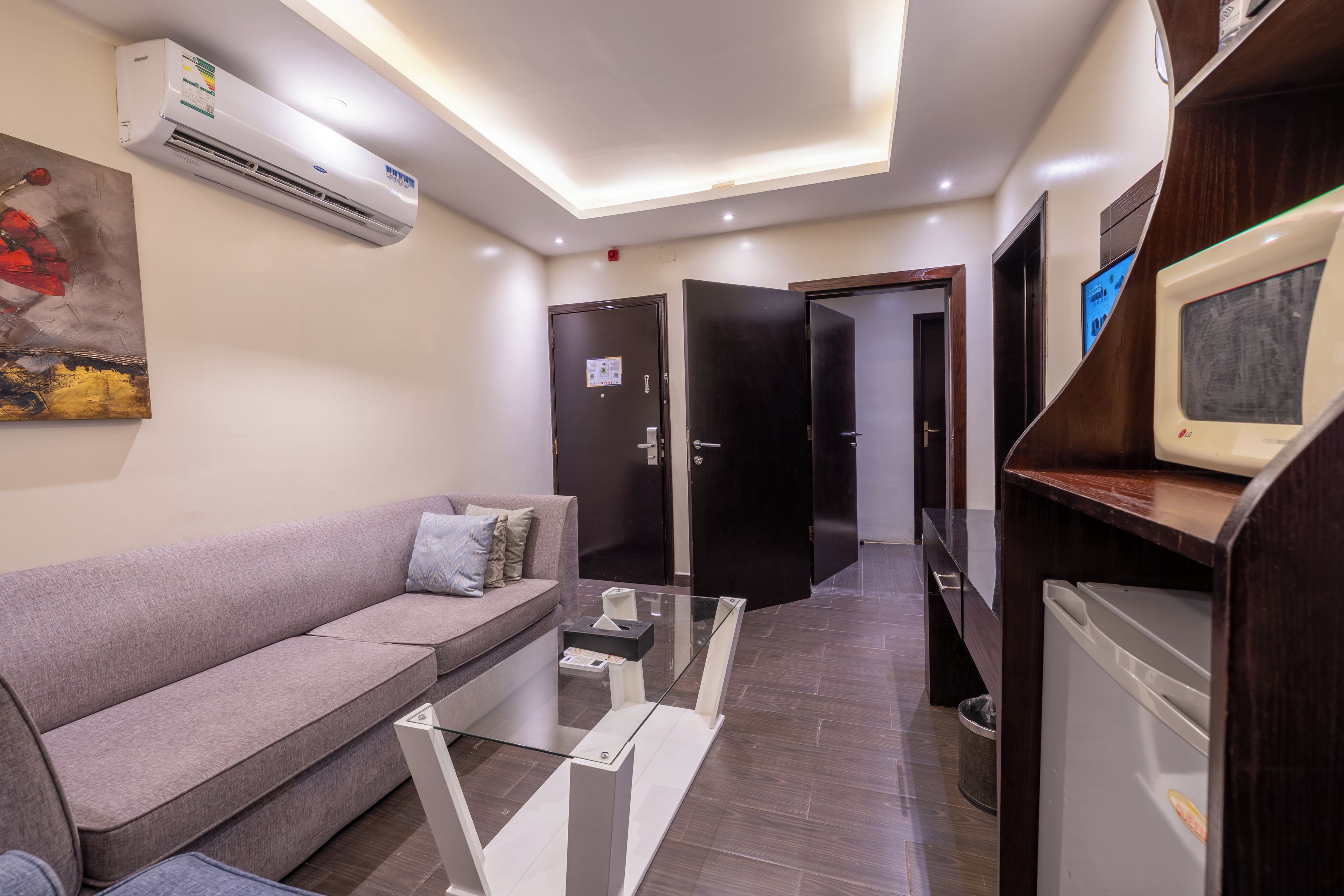 Una sala de estar moderna con un sofá, una mesa de centro de cristal y un televisor de pantalla plana sobre un mueble de madera.