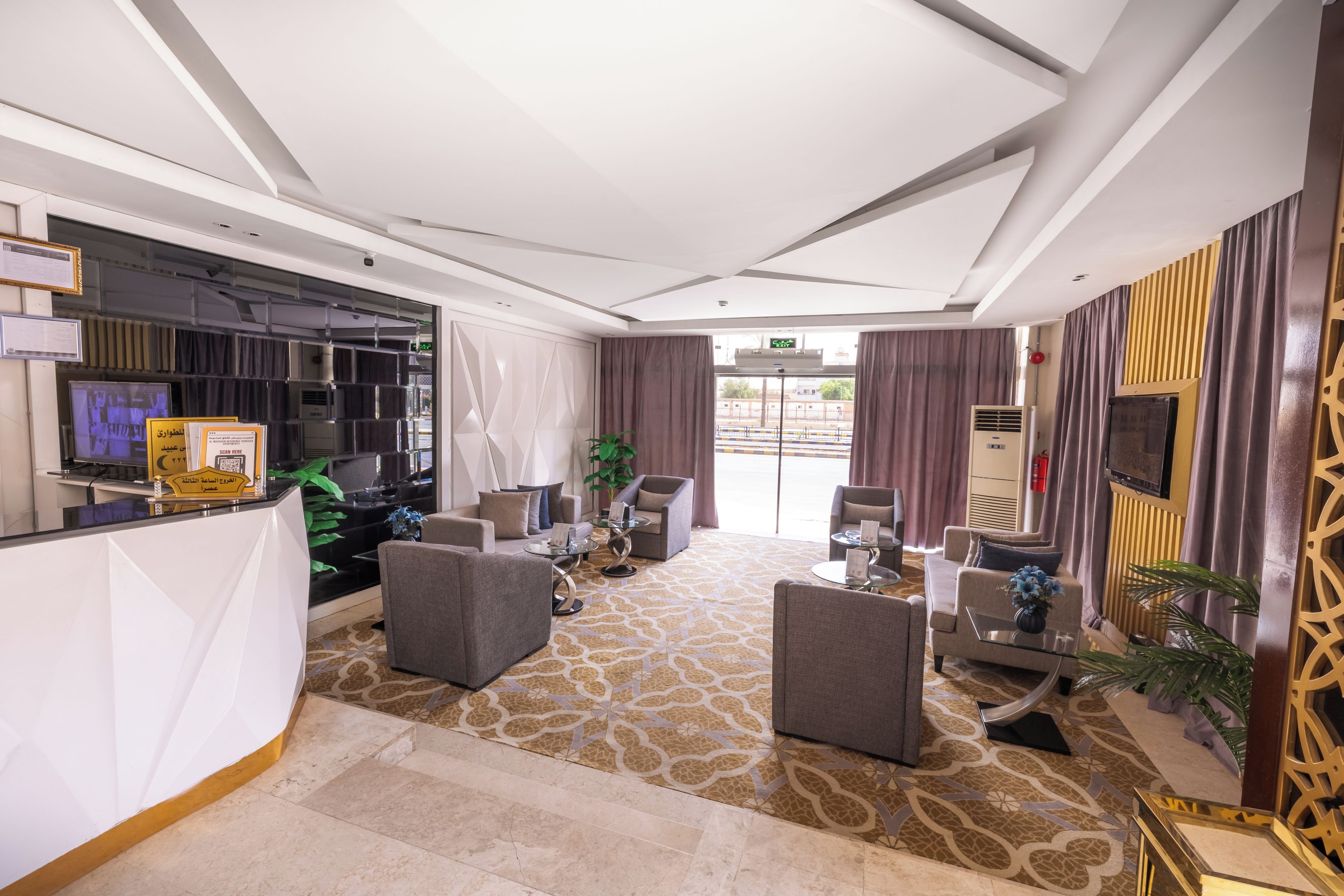 Um hall de hotel com balcão de recepção, área de estar e vista para o exterior.