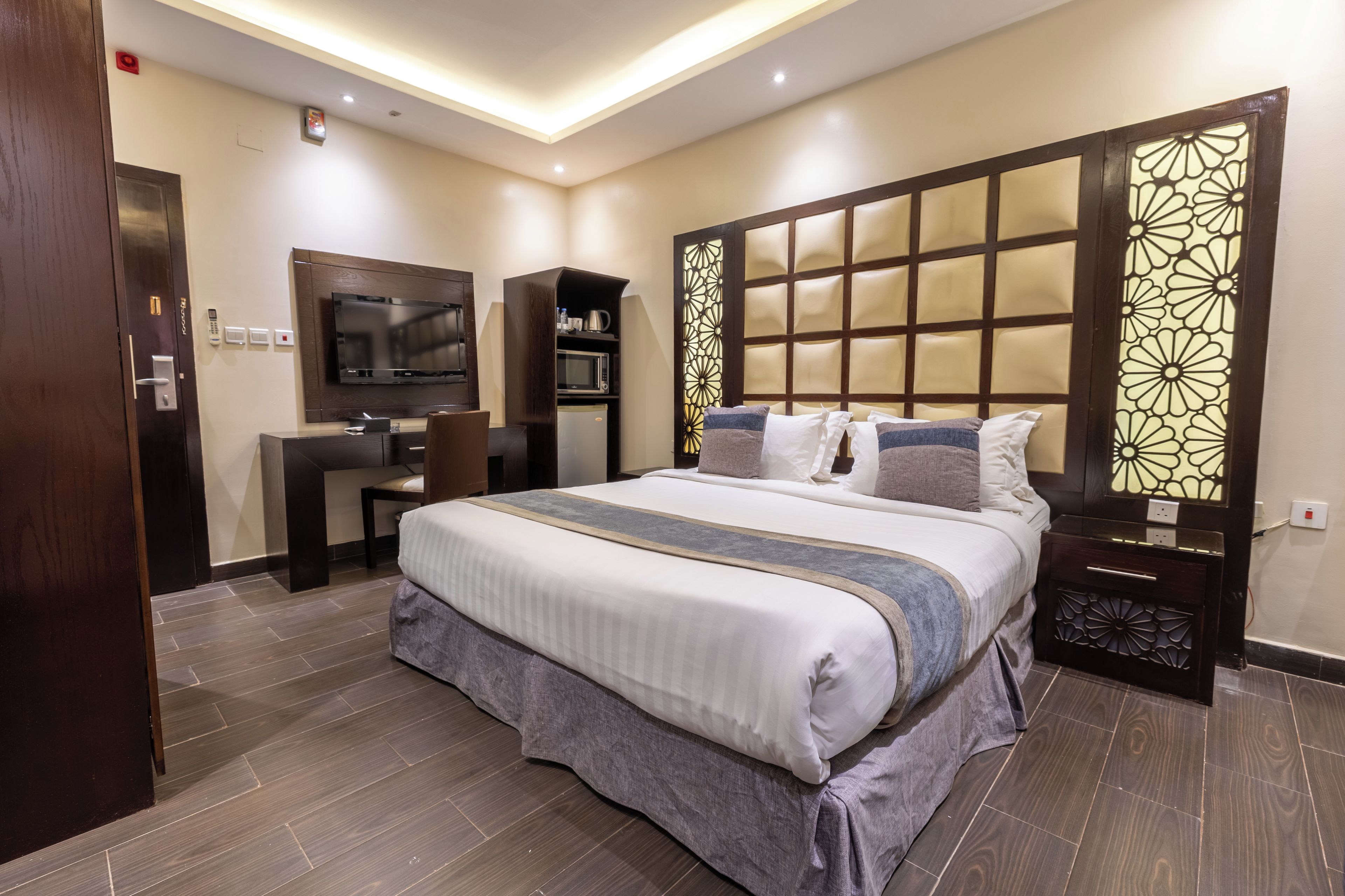 Una habitación de hotel moderna con una cama grande, un escritorio, un televisor y un minibar.