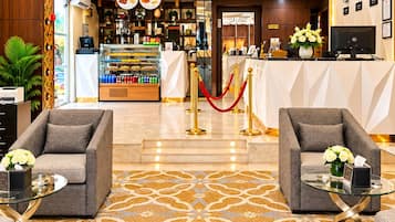 Un vestíbulo de hotel con mostrador de recepción, zona de estar y un bar.