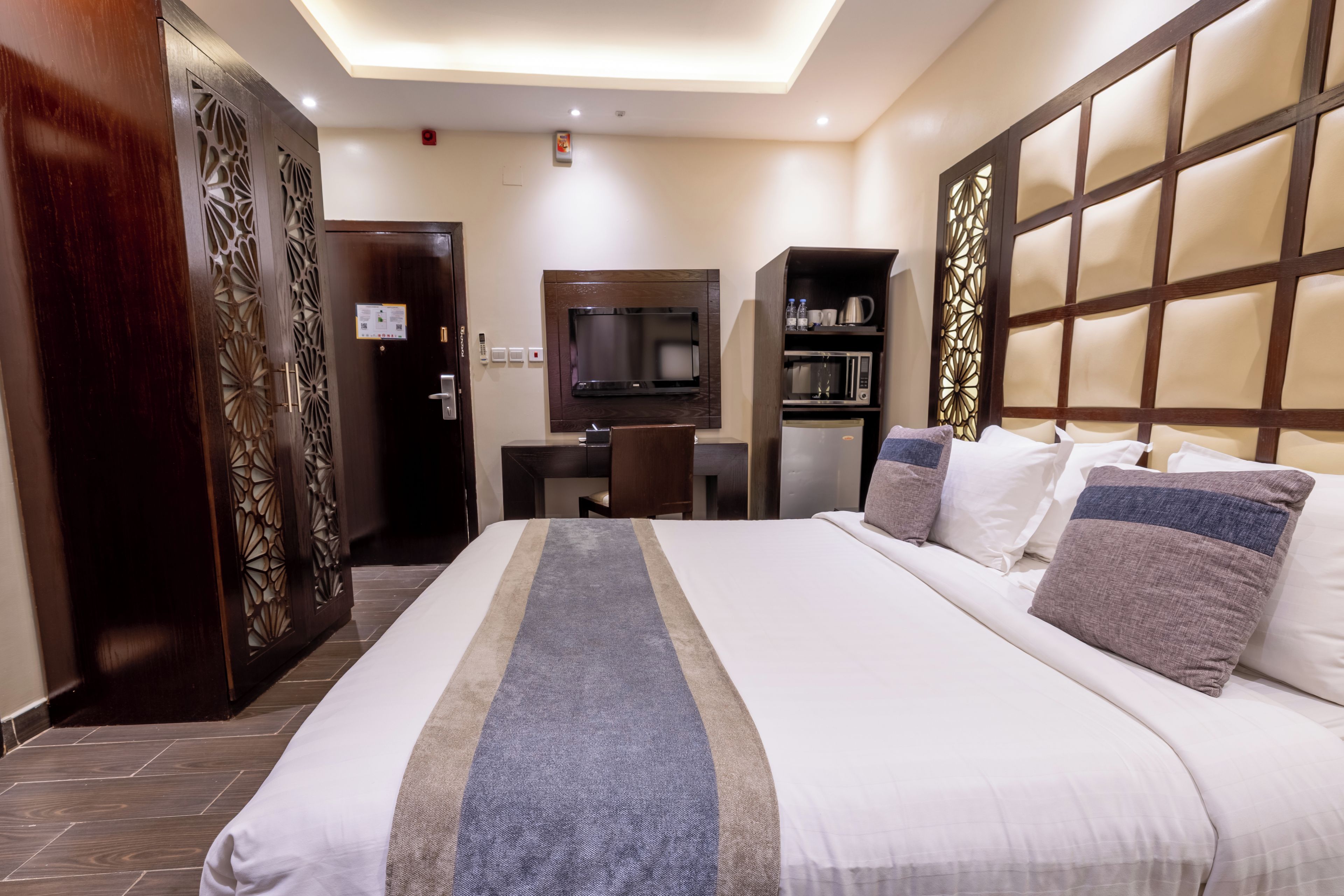 A hotel room with a large bed, a television, a microwave, and a minibar.