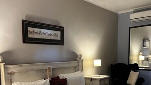 Una habitación de hotel con cama, mesita de noche, lámpara, silla y espejo.