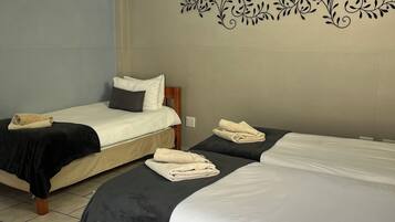 Habitación de hotel con dos camas, cada una con cubrecama blanco y negro, y un diseño decorativo en la pared.