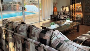 Una sala de estar con un sofá grande, una mesa de centro y vistas a una piscina.