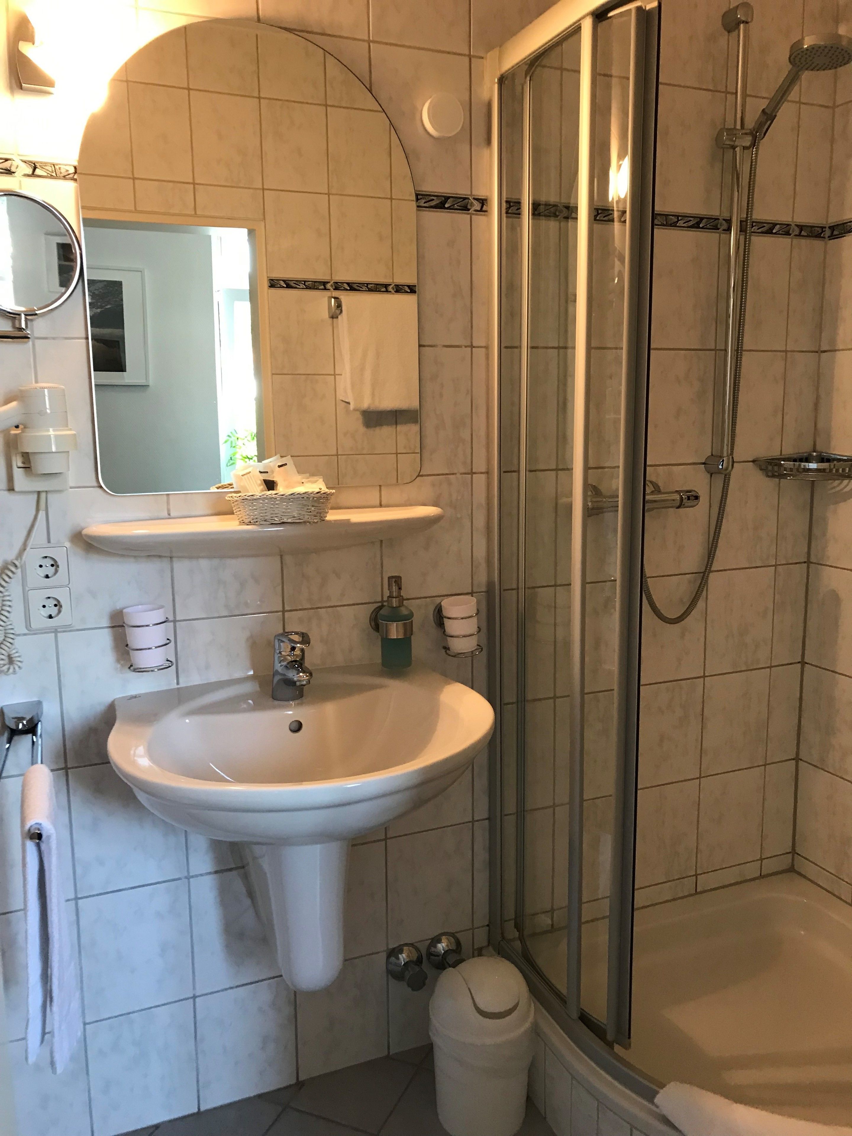 A bathroom with a sink, mirror, towel rack, and shower.