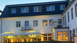 A building with a balcony and outdoor seating area with umbrellas.