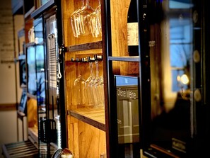 A wooden wine rack with multiple wine glasses and a wine bottle.