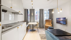 A modern kitchen with a dining area, a sofa, and a TV. - VANDER - Sea Story (Stavanger)