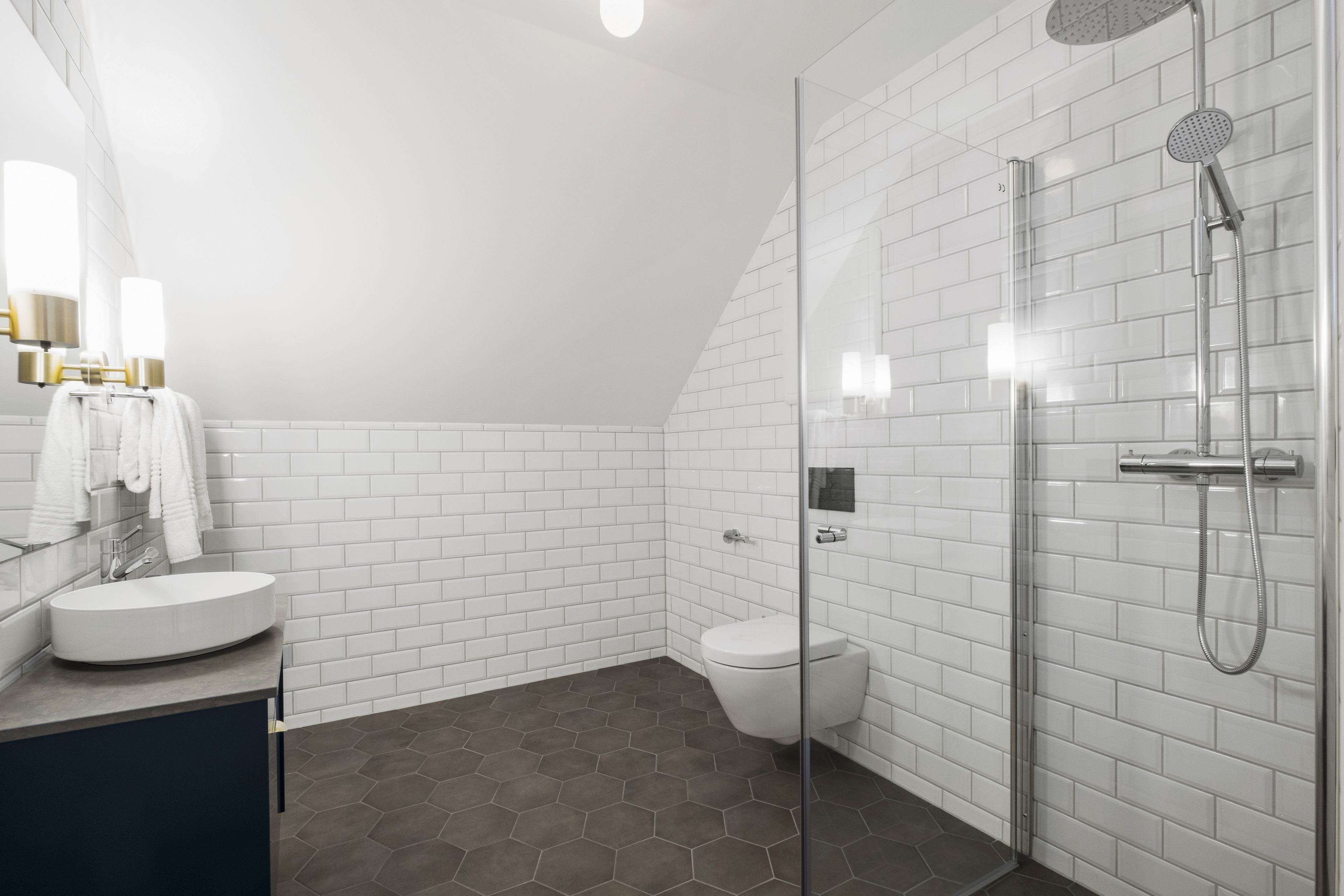 A modern bathroom with a glass shower enclosure, white subway tiles, and a round sink.