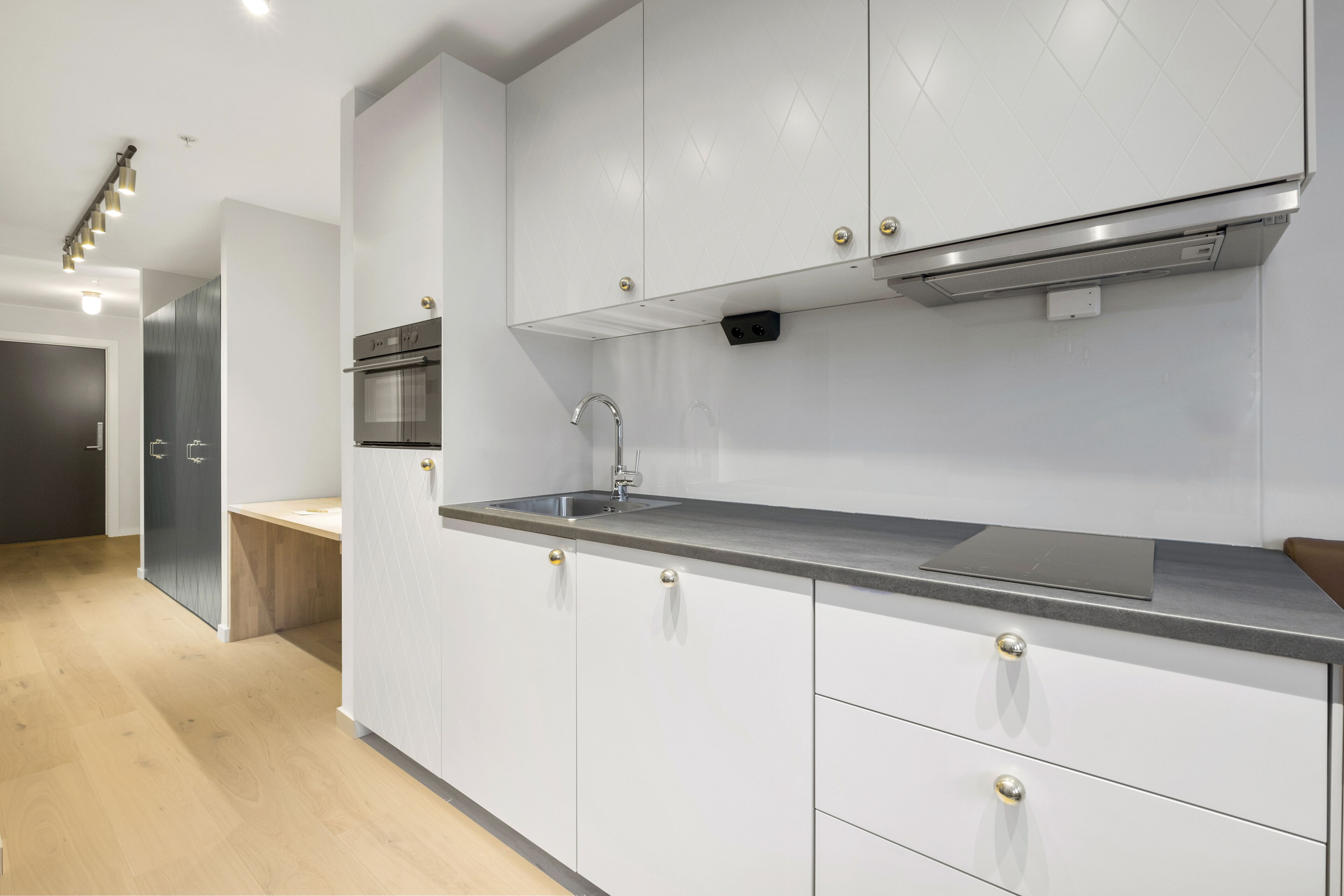 Une cuisine moderne avec des meubles blancs, des appareils en acier inoxydable et un plan de travail en bois.