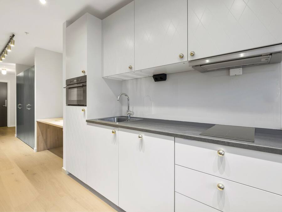 Una cucina moderna con mobili bianchi, elettrodomestici in acciaio inossidabile e un piano di lavoro in legno.
