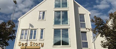 A white multi-story building with the sign "Sea Story By Frogner House Apartments" on the front.