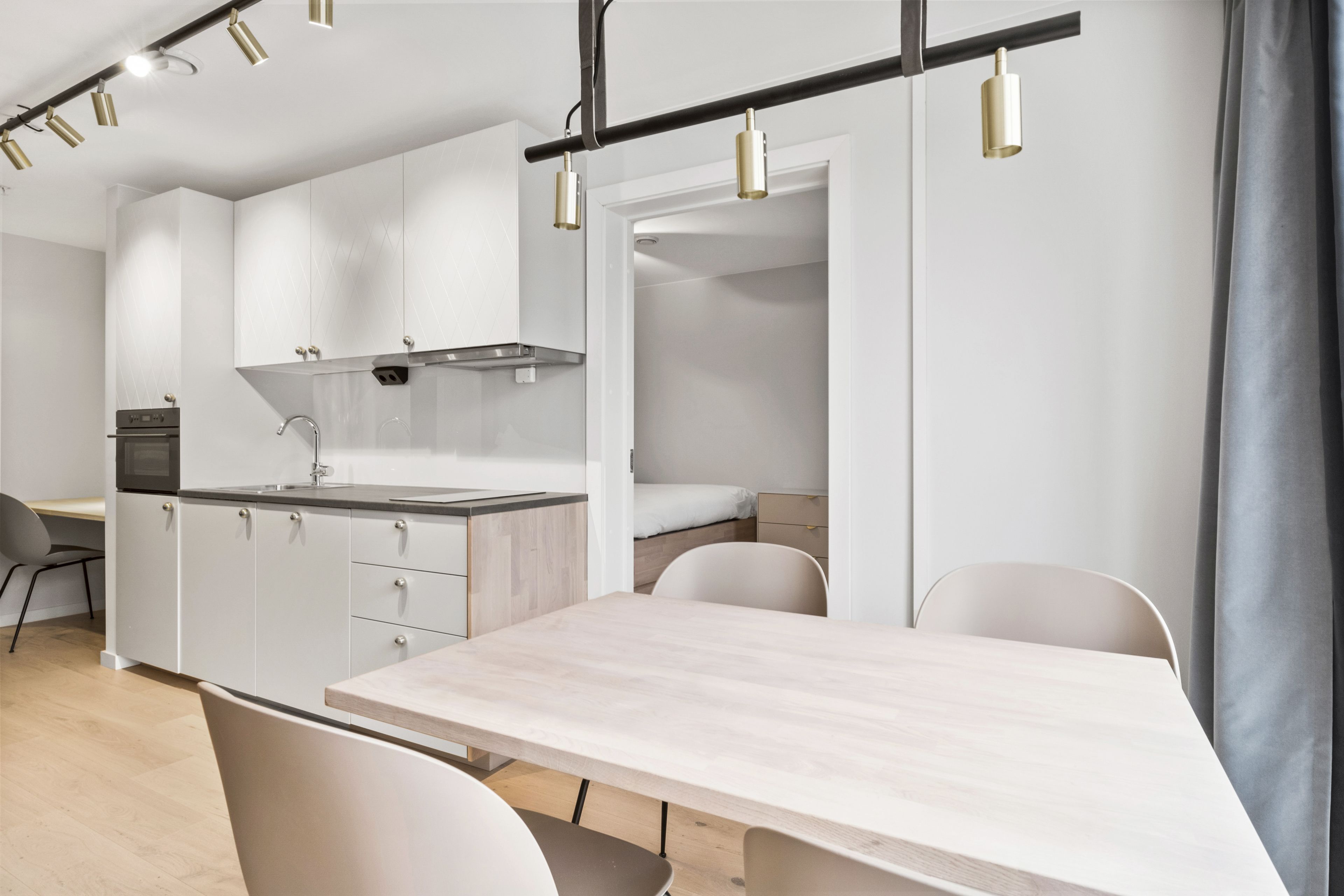 A modern kitchen with white cabinets, a wooden countertop, and a dining area with a table and chairs.