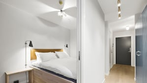 A modern bedroom with a wooden headboard, a bedside table, and a nightstand. - VANDER - Sea Story (Stavanger)