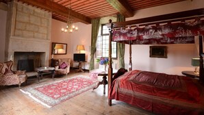 Une chambre traditionnelle avec un lit à baldaquin, une cheminée en pierre et un mobilier classique.