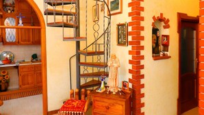 A spiral staircase with a metal railing, wooden cabinets, a small table with a red cloth, and a brick archway. - B&B La Maison De Titty & Margy (Piano di Sorrento)
