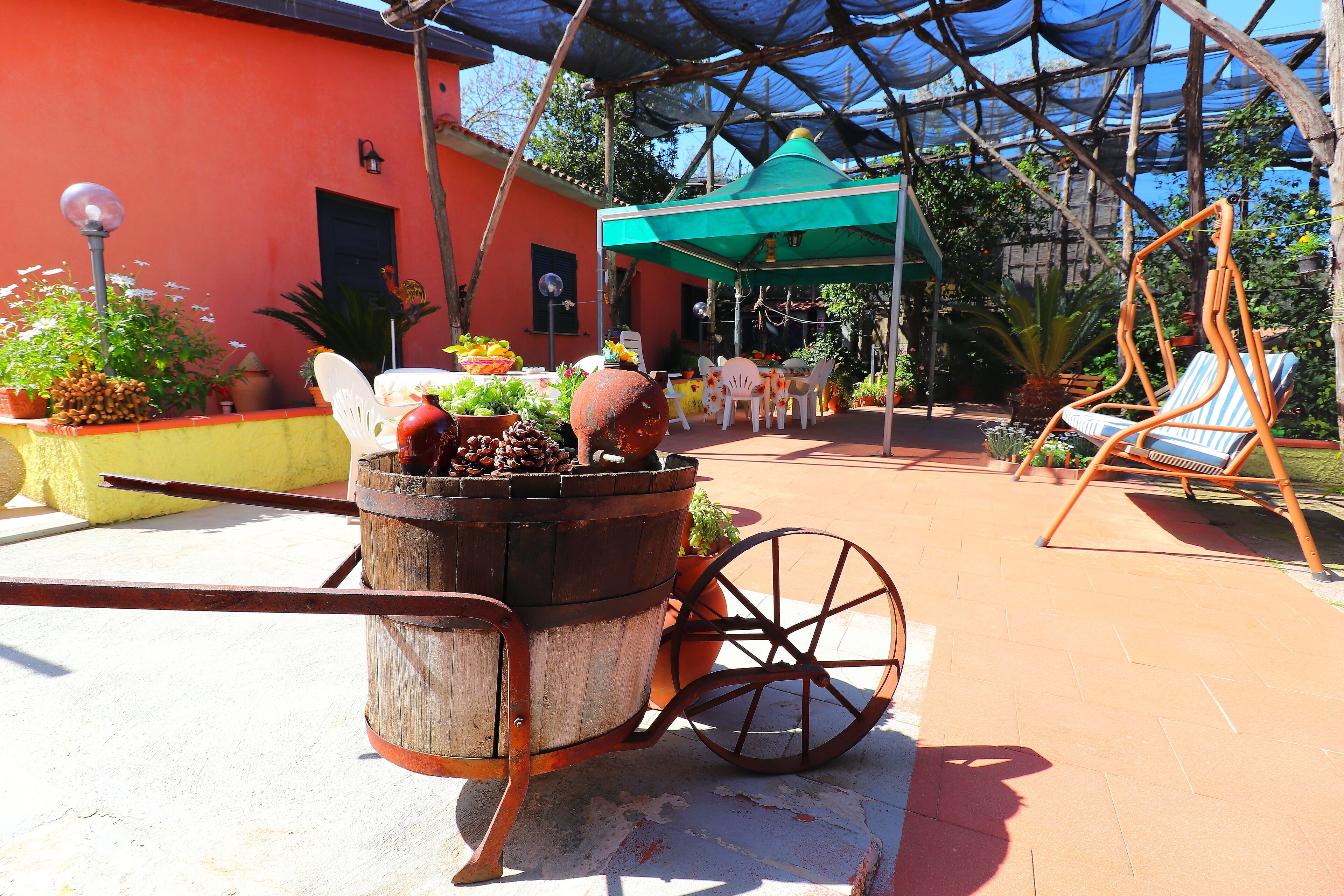 A rustic outdoor seating area with a wooden cart, a covered patio, and a swing chair.