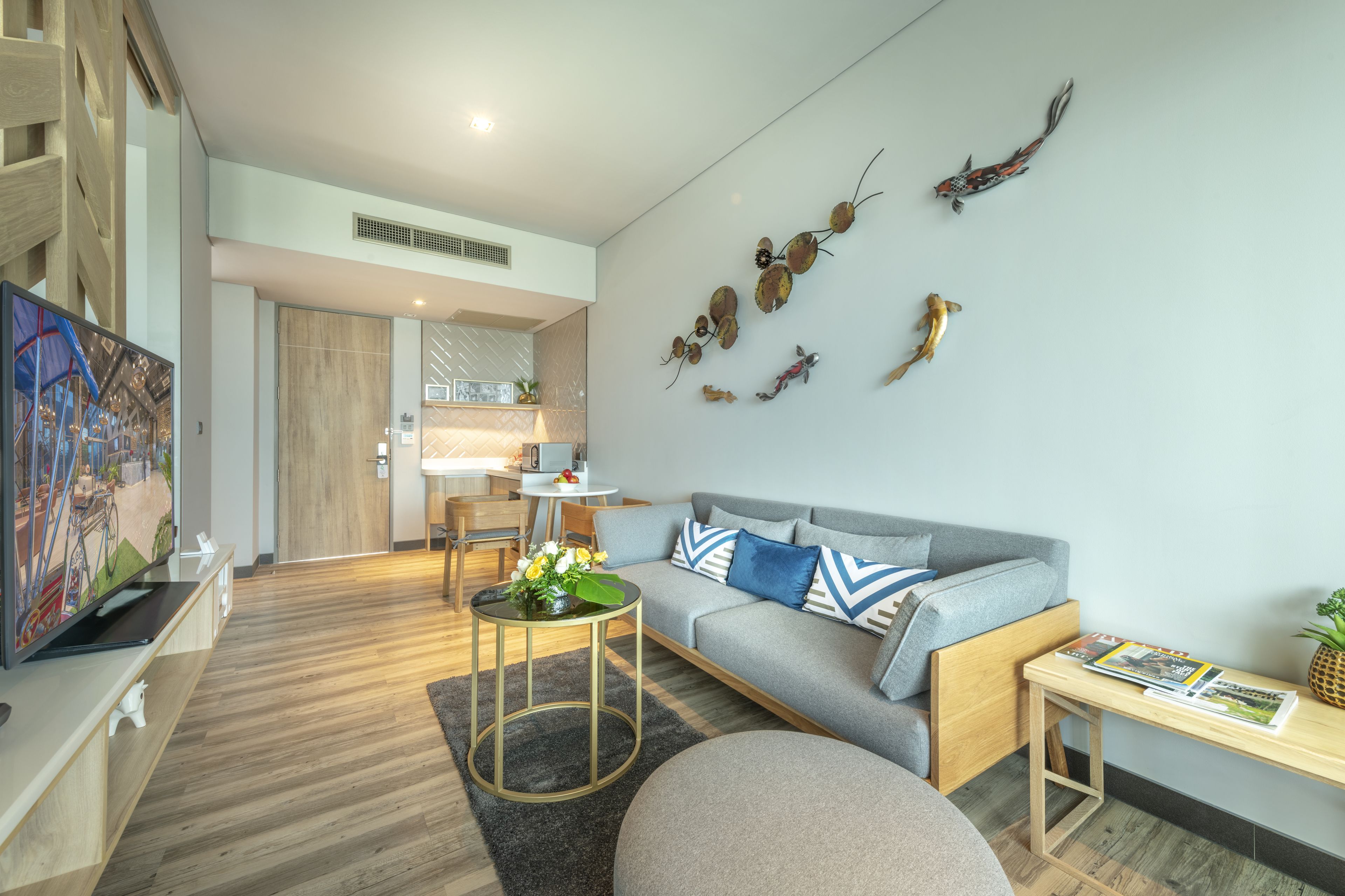 Ein modernes Wohnzimmer mit grauem Sofa, Couchtisch aus Holz und dekorativer Wandgestaltung.
