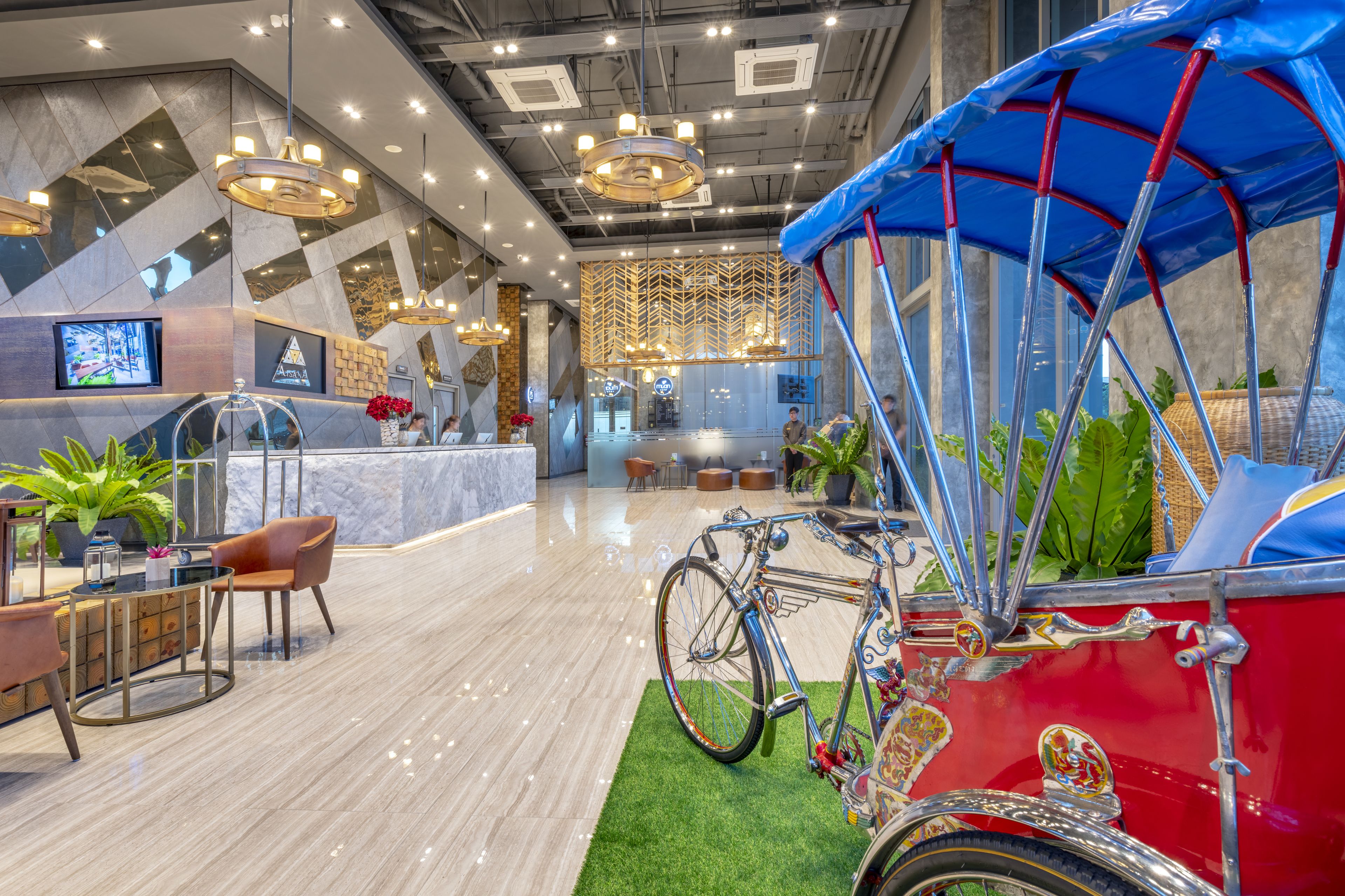 A modern hotel lobby with a vintage car, seating area, and a large screen.