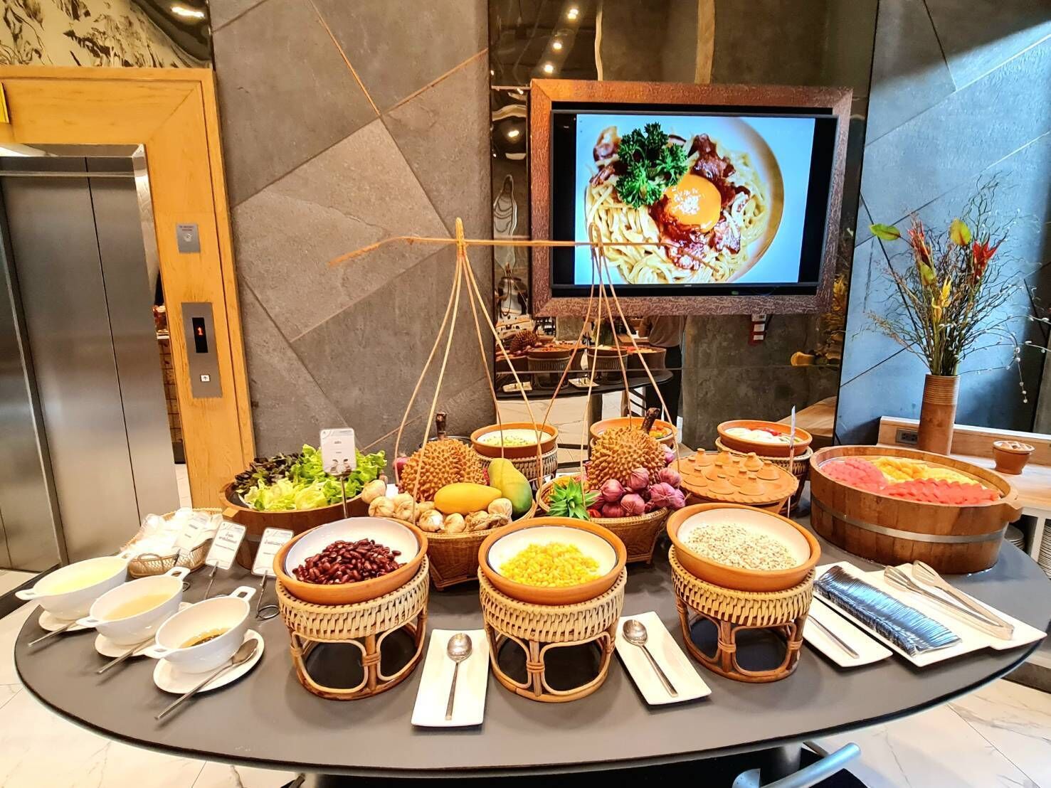 A buffet setup with various food items and a television displaying a meal.