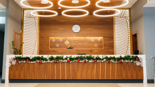 A reception desk with a wooden finish, a clock, and a sign that reads "The Square".