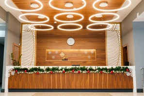 A reception desk with a wooden finish, a clock, and a sign that reads "The Square". - The Square Hotel (Astana)