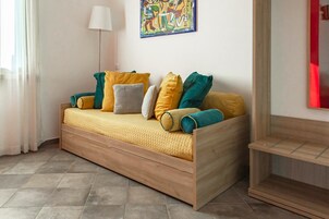 Una habitación moderna con un sofá cama de madera, una lámpara de pie y un colorido cuadro abstracto en la pared.