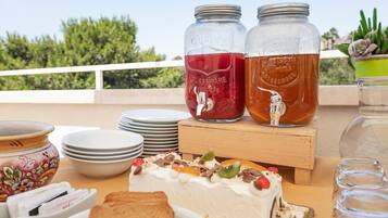 A table with a cake, two mason jars with drinks, and a potted plant.