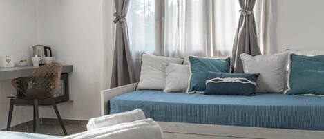 Una habitación de hotel moderna con una cama, un escritorio con hervidor y una silla.
