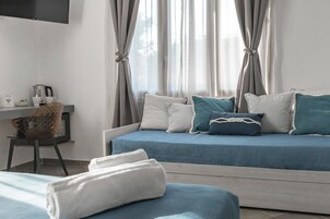 Una habitación de hotel moderna con una cama, un escritorio con hervidor y una silla.