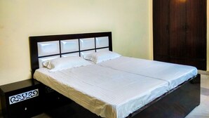 A double bed with a black headboard and white bedding in a room with a wooden wardrobe and a nightstand with a label. - The Desire Hostel (New Delhi)