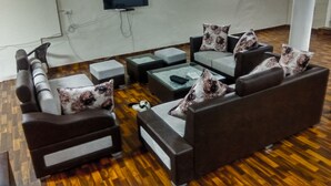 A living room with a sofa set, a coffee table, and a flat-screen TV mounted on the wall. - The Desire Hostel (New Delhi)